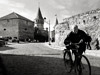 photograph of an old man walking his bicycle down the street in front of kamenets podolski fortress in ukraine