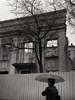 black and white picture using a 1938 zeiss ikonta 520 of the destruction of a turn of the century building in kiev near arsenal factory for making a new modern building in the rain wiht a woman holding an umbrella